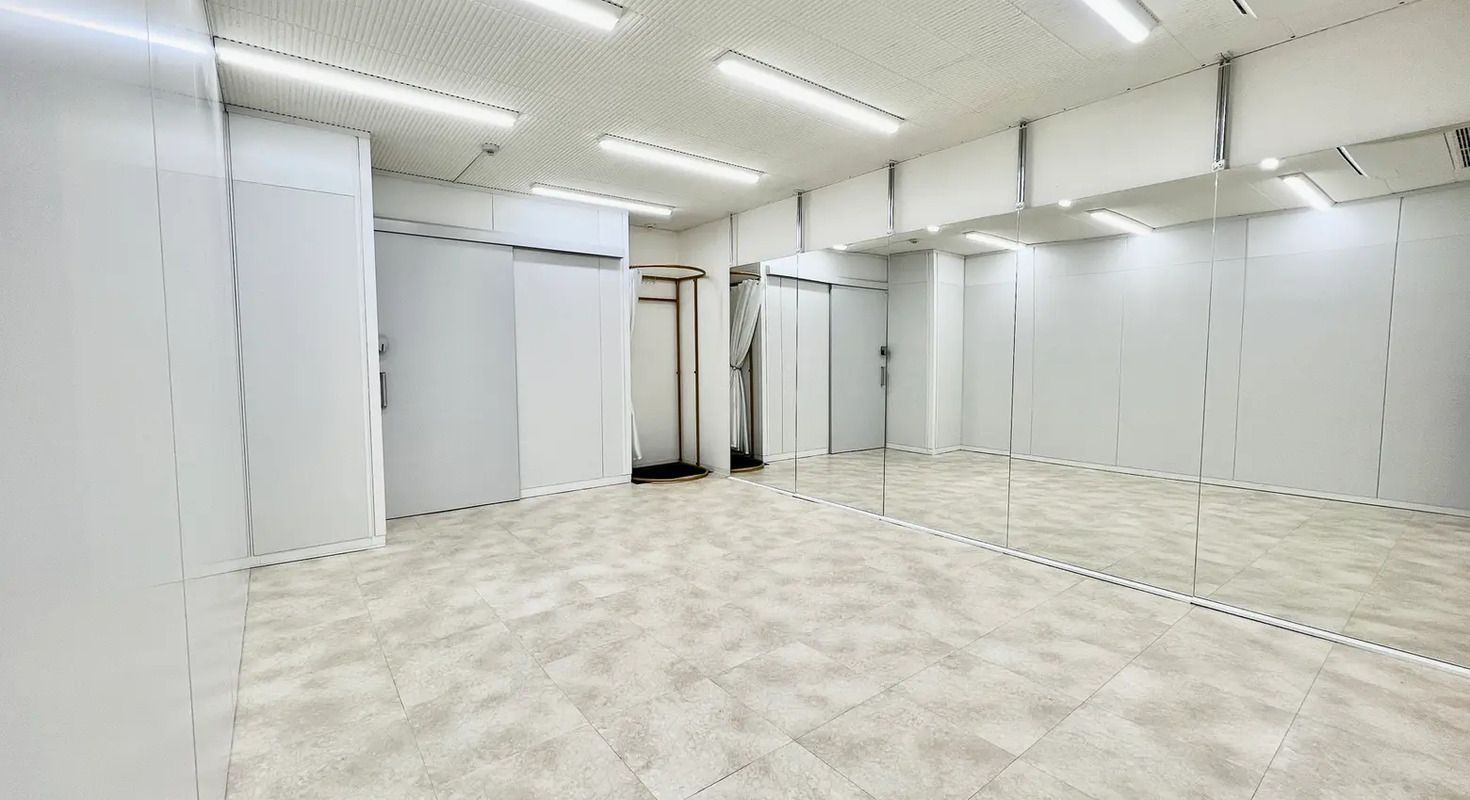 壁一面に鏡が設置された、清潔で広々としたスタジオスペース。ダンスやリハーサルに適した空間です。