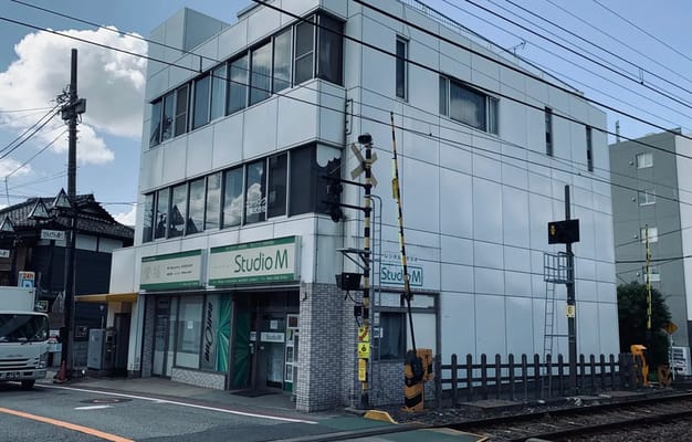 踏切の近くに位置するStudio Mの全体的な建物構造が見える。